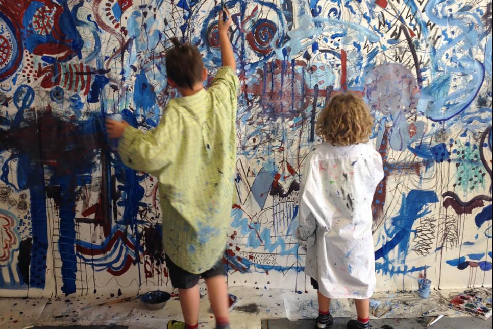 Two children painting a mural on a wall.