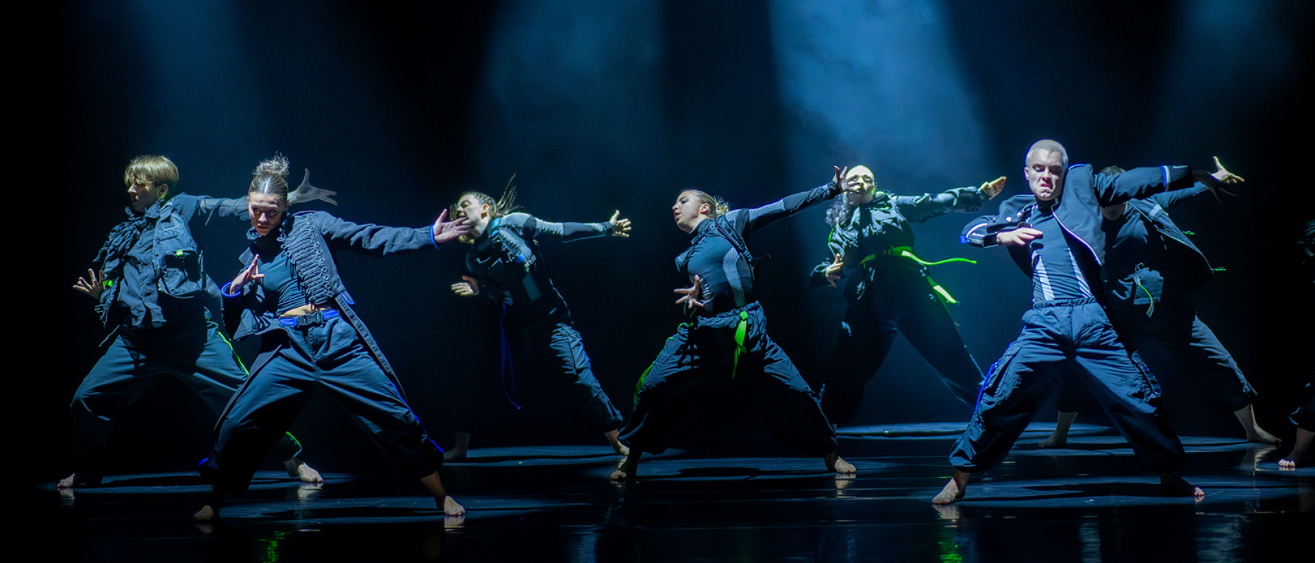 Dancers strike a pose on stage under blue lighting