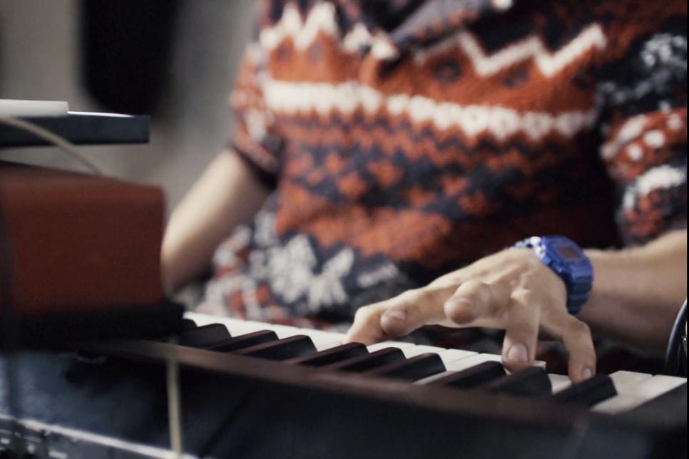 Man in a colourful jumper playing the keyboard