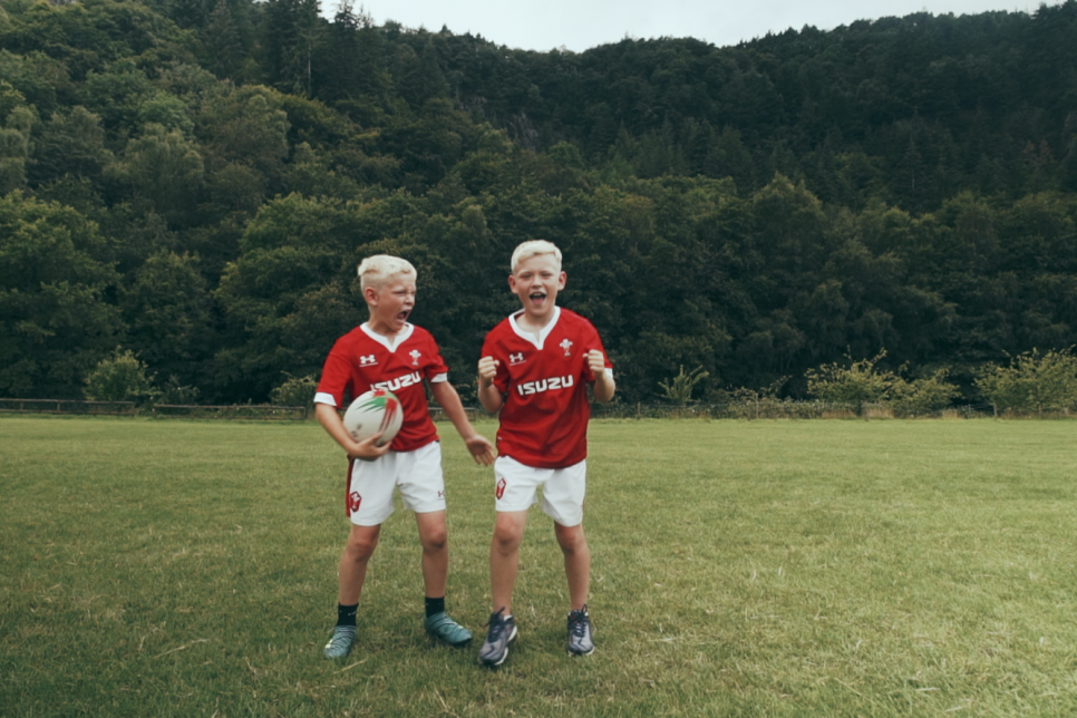 Two young boys playing rugby in Welsh kits