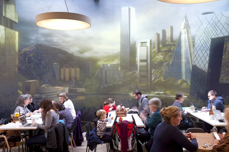 People sitting at tables in front of a wall mural