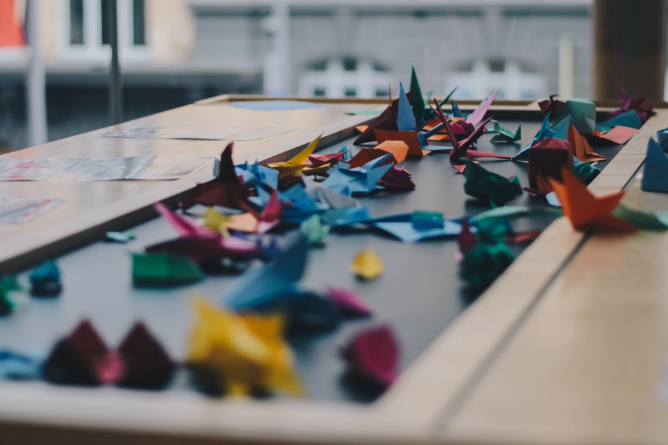 Origami lliwgar ar fwrdd | Colourful origami on a table. Image by Dev Benjamin