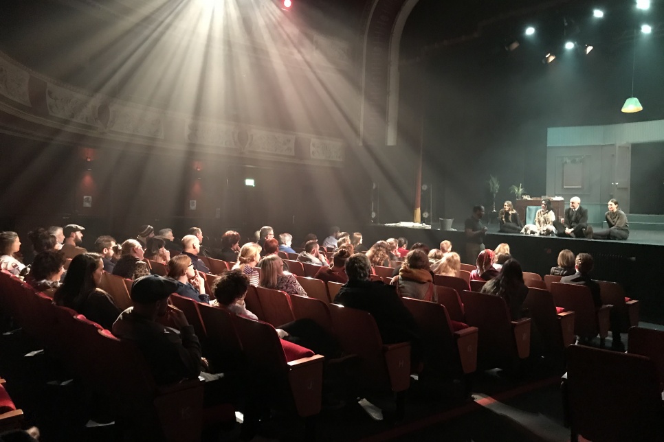 Cynulleidfa mewn theatr yn gwylio cynhyrchiad ar lwyfan | An audience in a theatre looking at a production on stage.