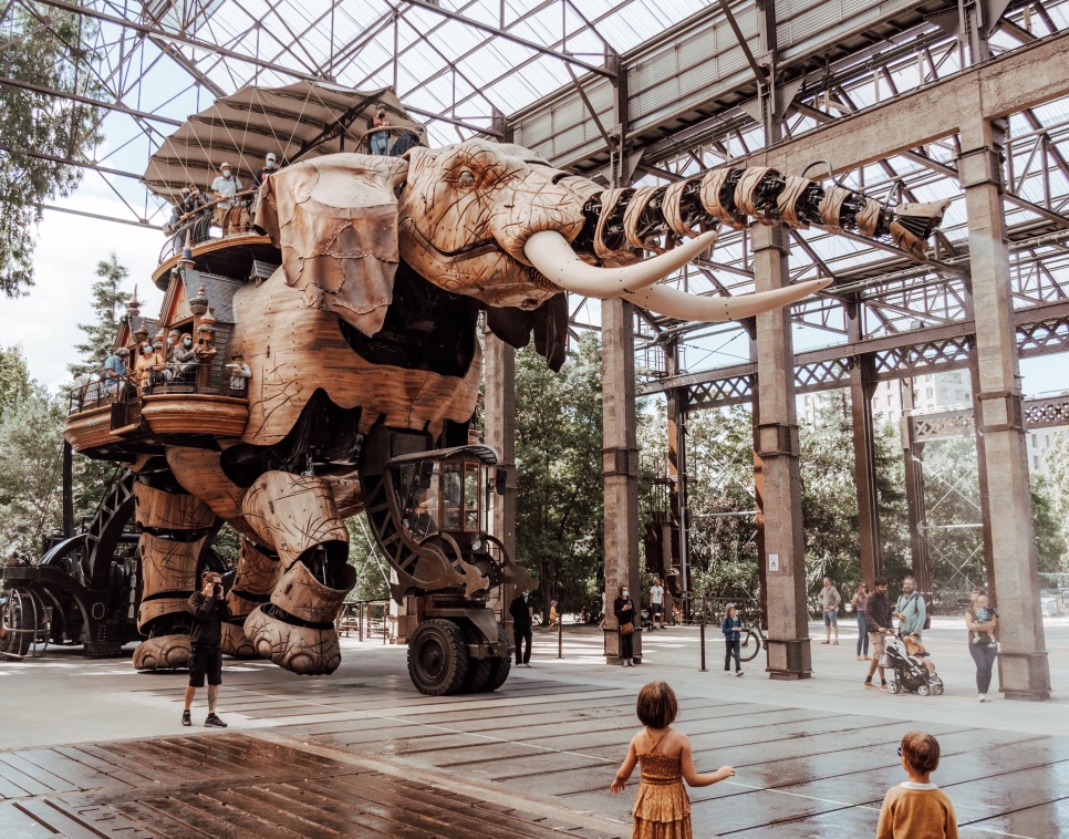 Giant metal sculpture of an elephant with people stood around it.