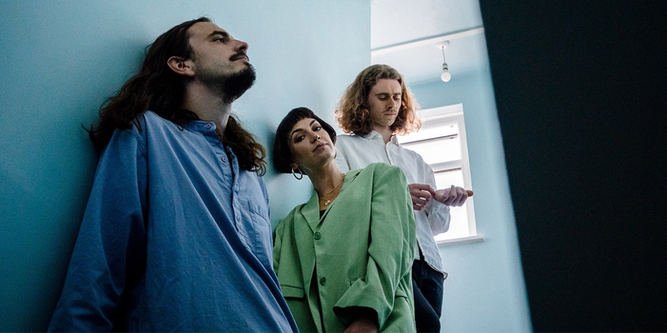 3 people leaning left against a blue wall.