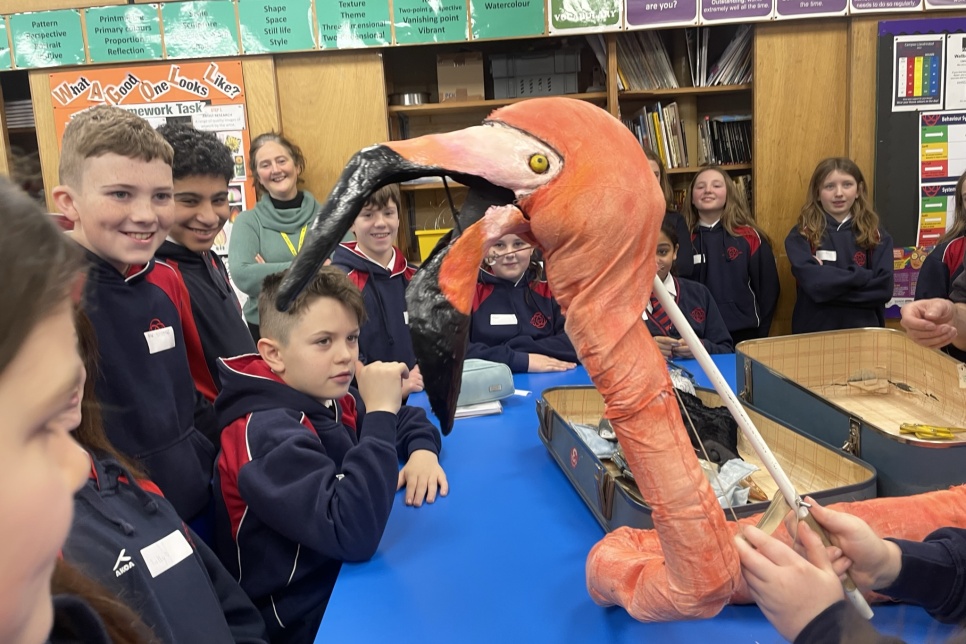 Pupils in a school looking at a puppet of a flamingo