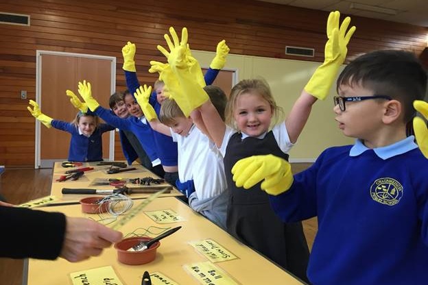 Pupils with their hands up in the air, wearing yellow rubber gloves