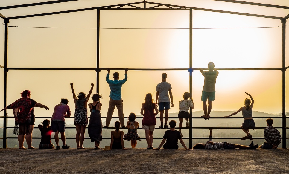 Group of people standing looking out over a sunset