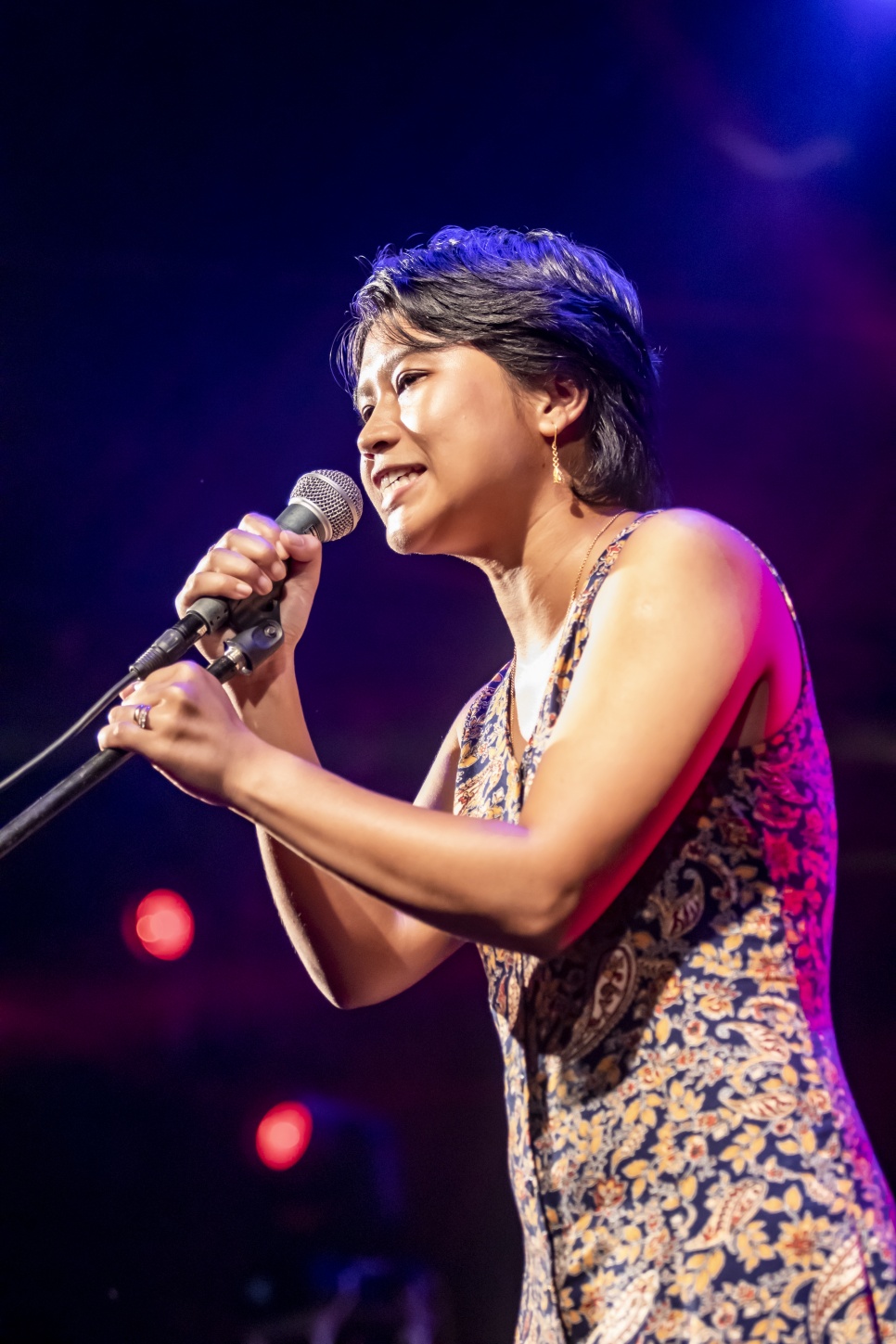 Credit: Goldrn Frame WHATFG 2022 Lapdiang Syiem singing on a stage in a floral dress with a hand-held microphone on a stand