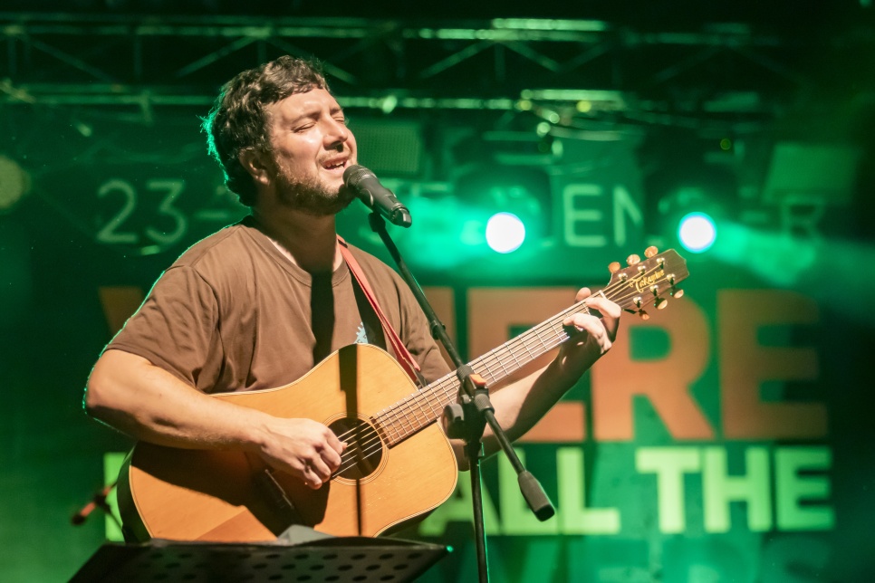 Credit: Golden Frame WHATFG 2022 Gareth Bonello singing and playing a guitar on stage with a microphone on a stand