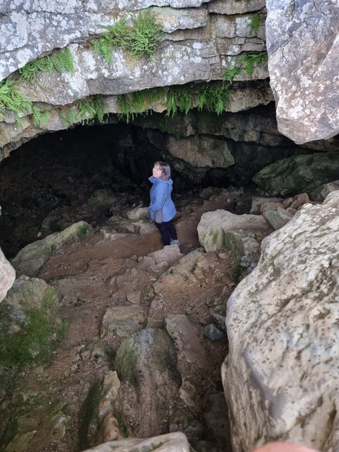 Credit: Georgina Biggs Georgina in the entrance to a rock cave wearing a blue rain coat