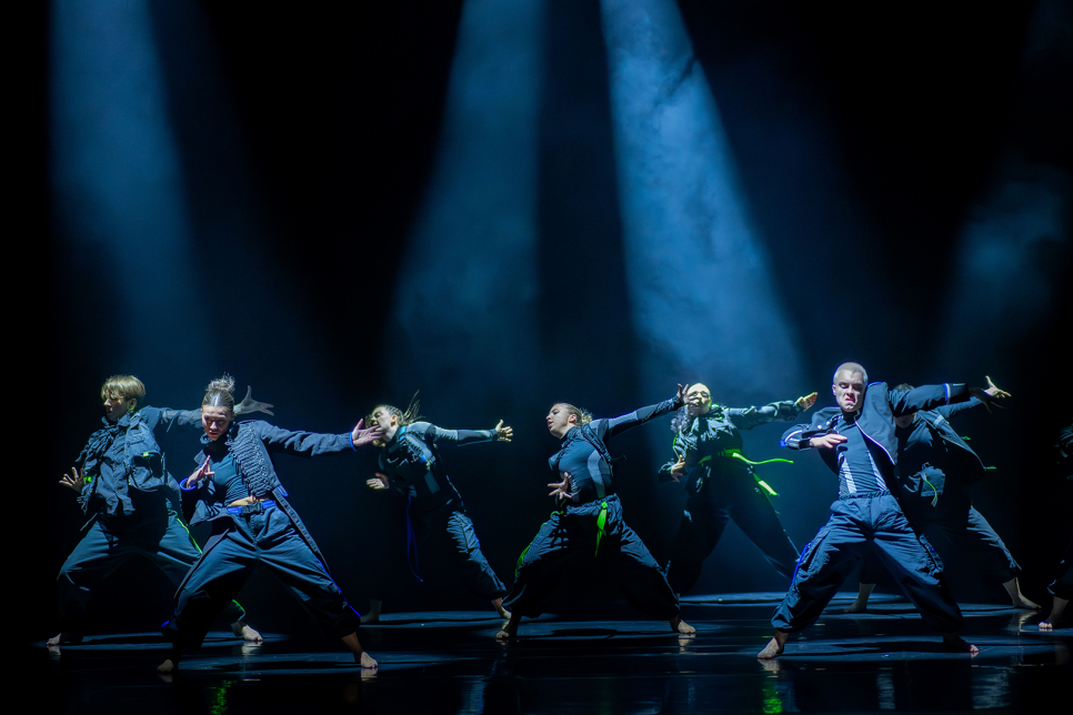Dancers strike a pose on stage under blue lighting