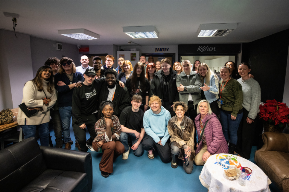 Photograph - Ed Sheeran and Amy Wadge with a group of people in an office / Ffotograff - Ed Sheeran ac Amy Wadge gyda chriw o bobl mewn swyddfa 