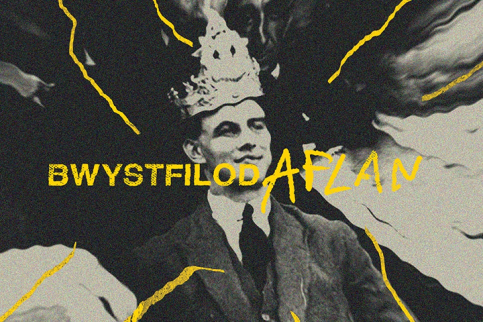 An image of a young man wearing a suit and tie and a crown on his head / Delwedd o ddyn ifanc yn gwisgo siwt a thei gyda choron ar ei ben