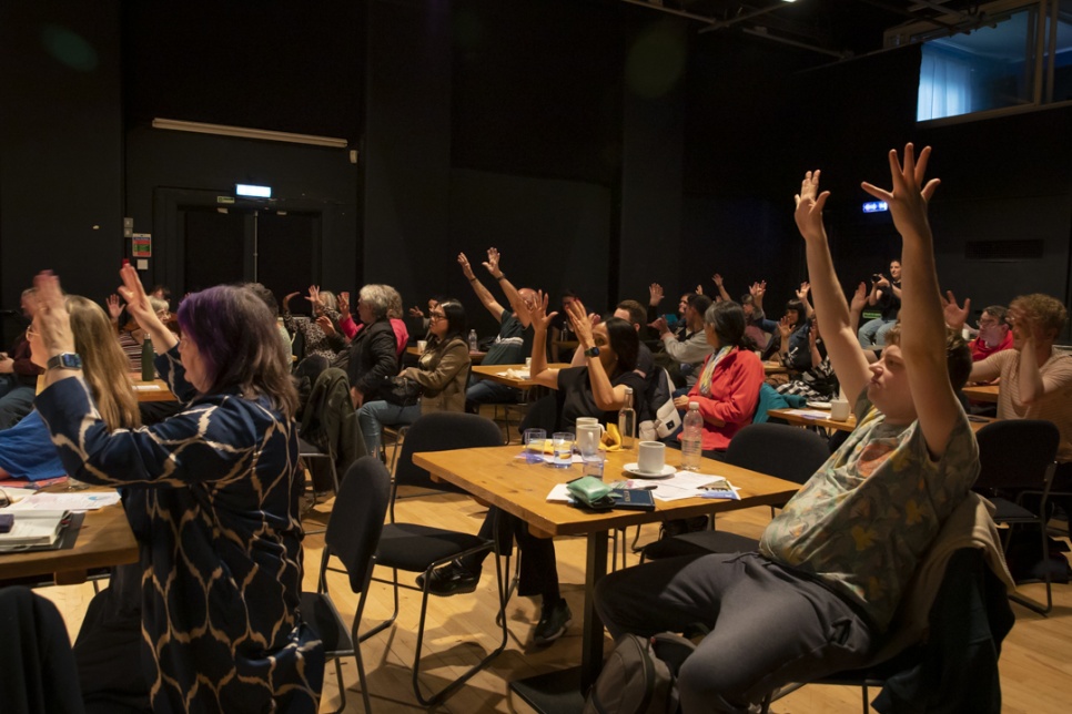 Attenders of Deaf Gathering Cymru Symposium applaud in BSL - arms above heads, waving hands / Mynychwyr Symposiwm Deaf Gathering Cymru yn cymeradwyo yn Iaith Arwyddion Prydain – breichiau uwchben y pen, yn chwifio dwylo